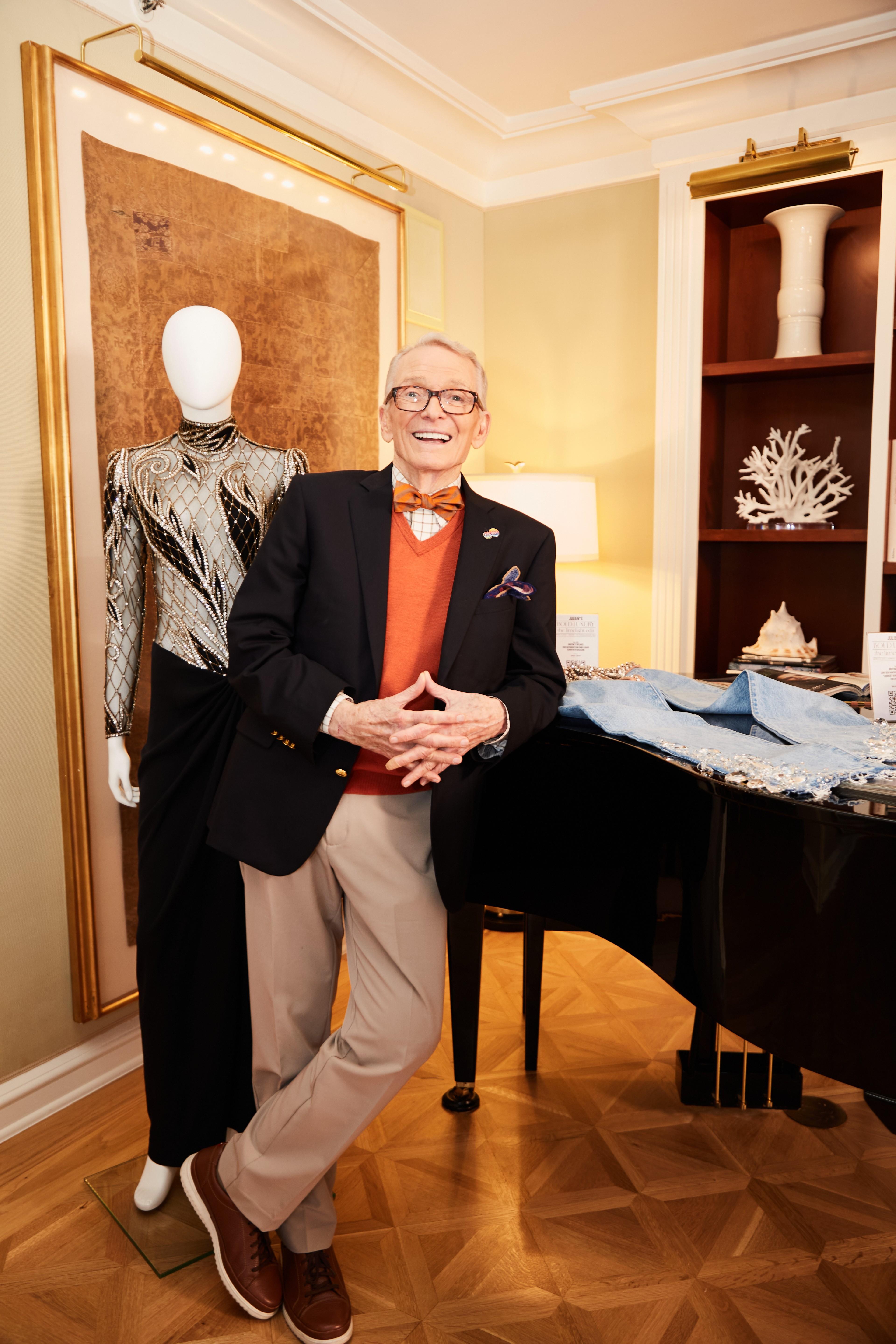 a man in a suit and bow tie stands in front of a piano