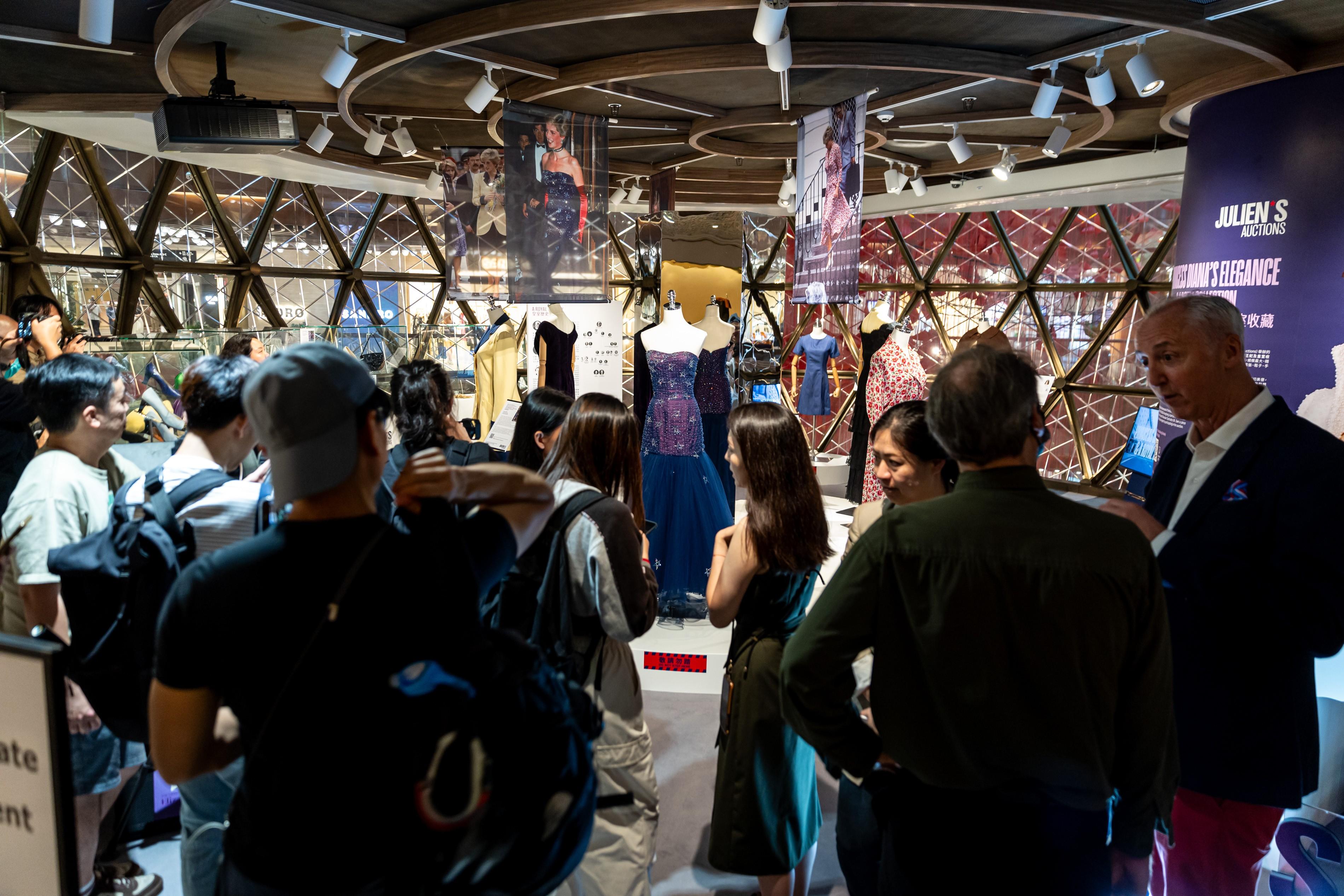 People in front of a display of dresses.
