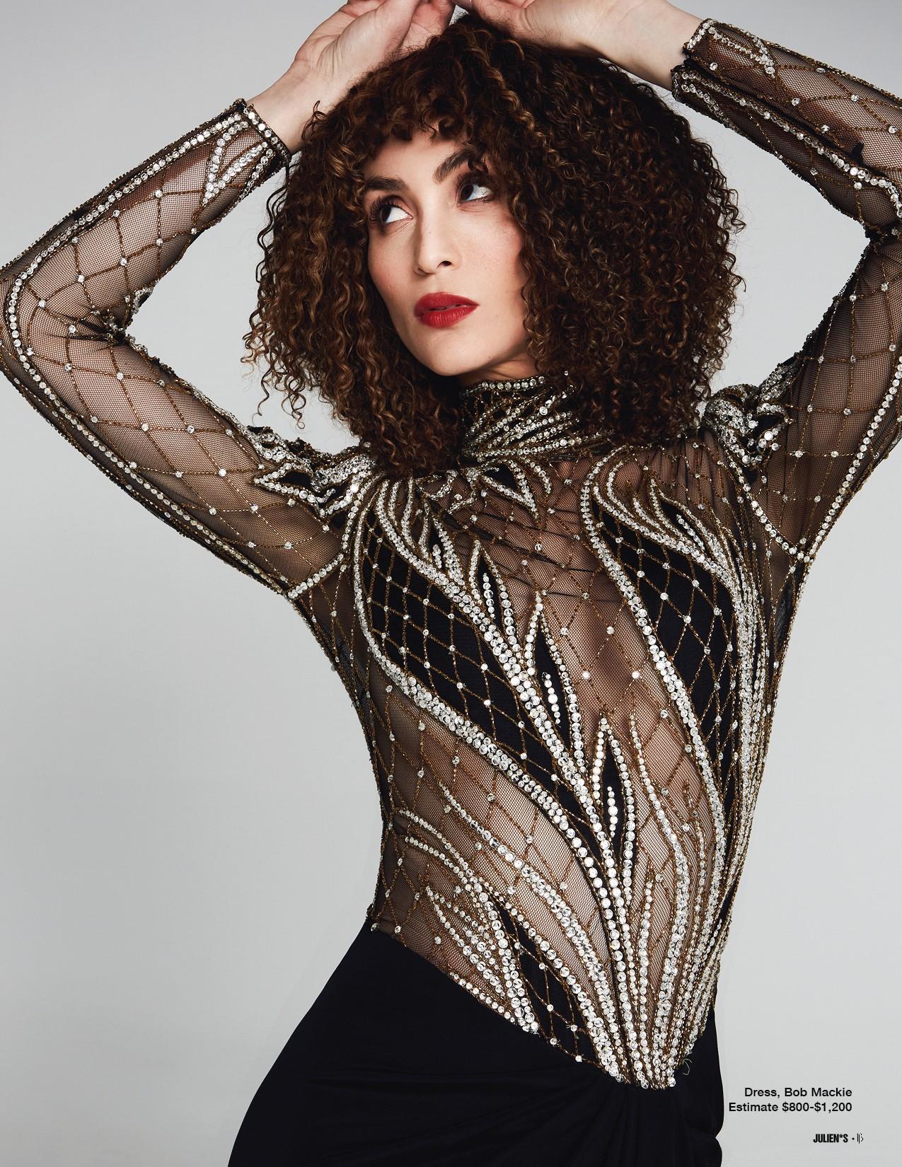 a woman with curly hair is wearing a black and silver dress