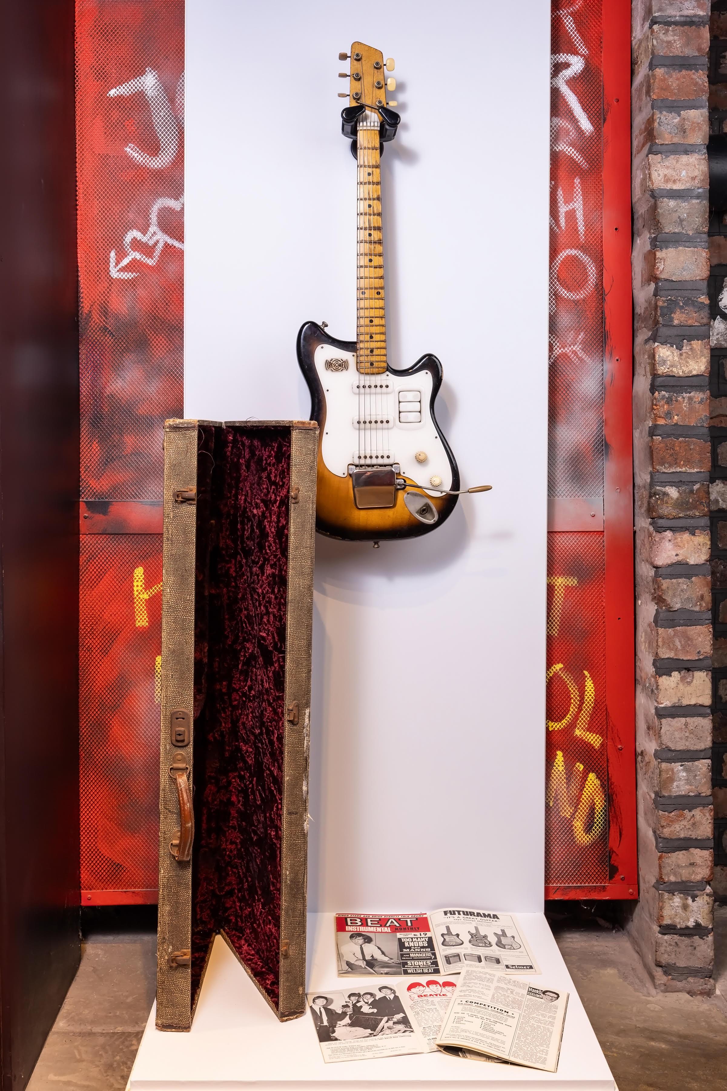a guitar is hanging on a wall next to a case