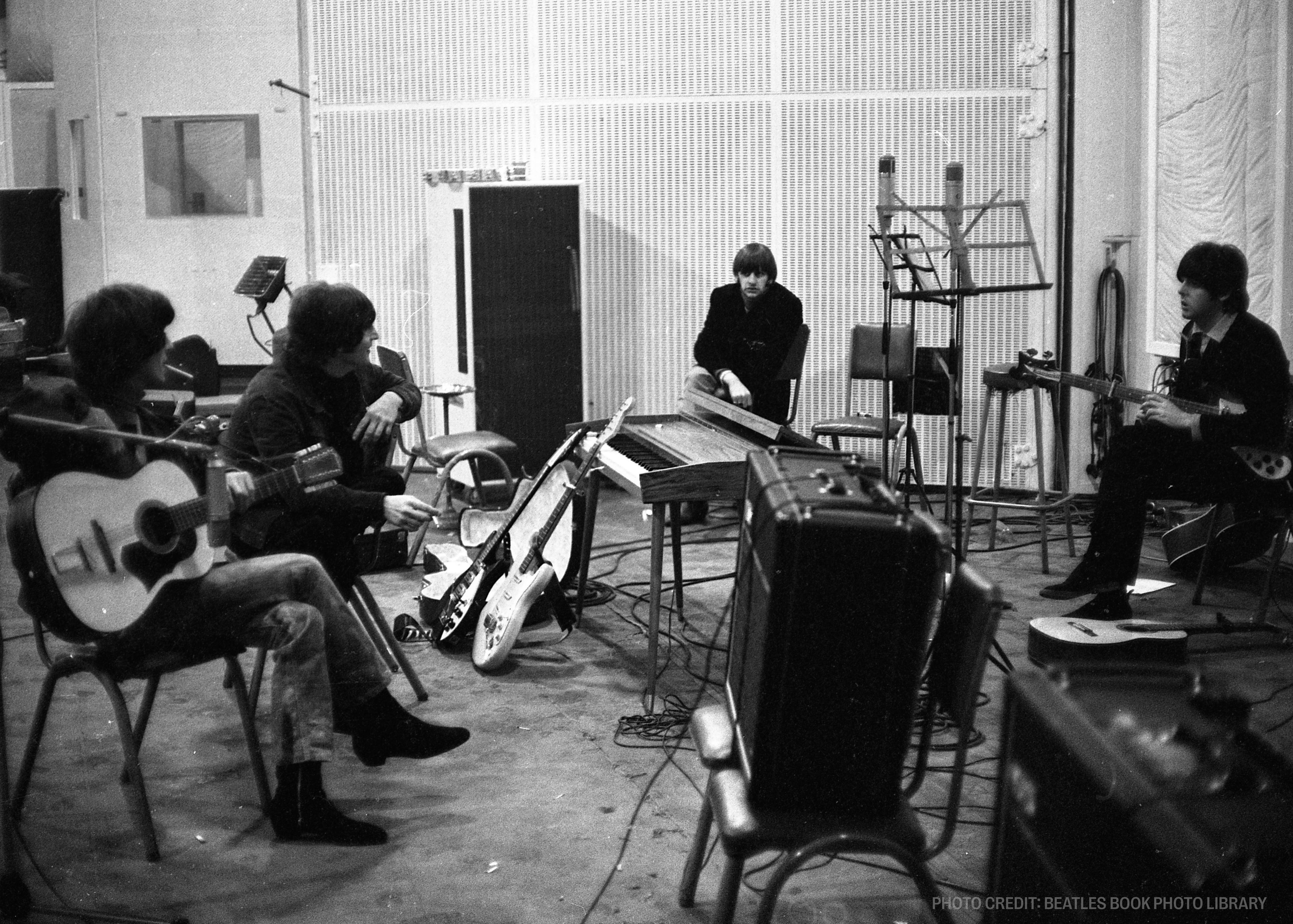 a black and white photo of the beatles playing guitars in a recording studio .
