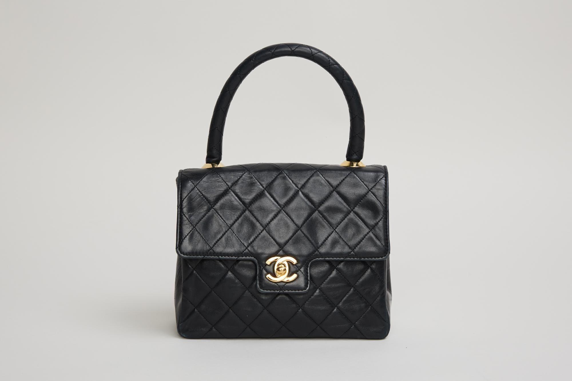 a black chanel bag with a black handle on a white background .