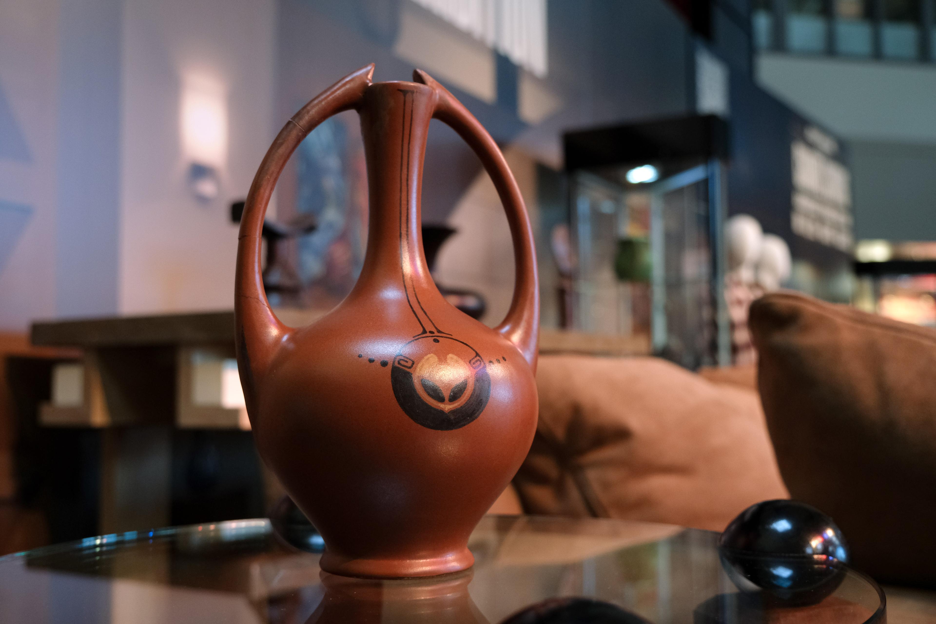 a clay red vase sitting on a table