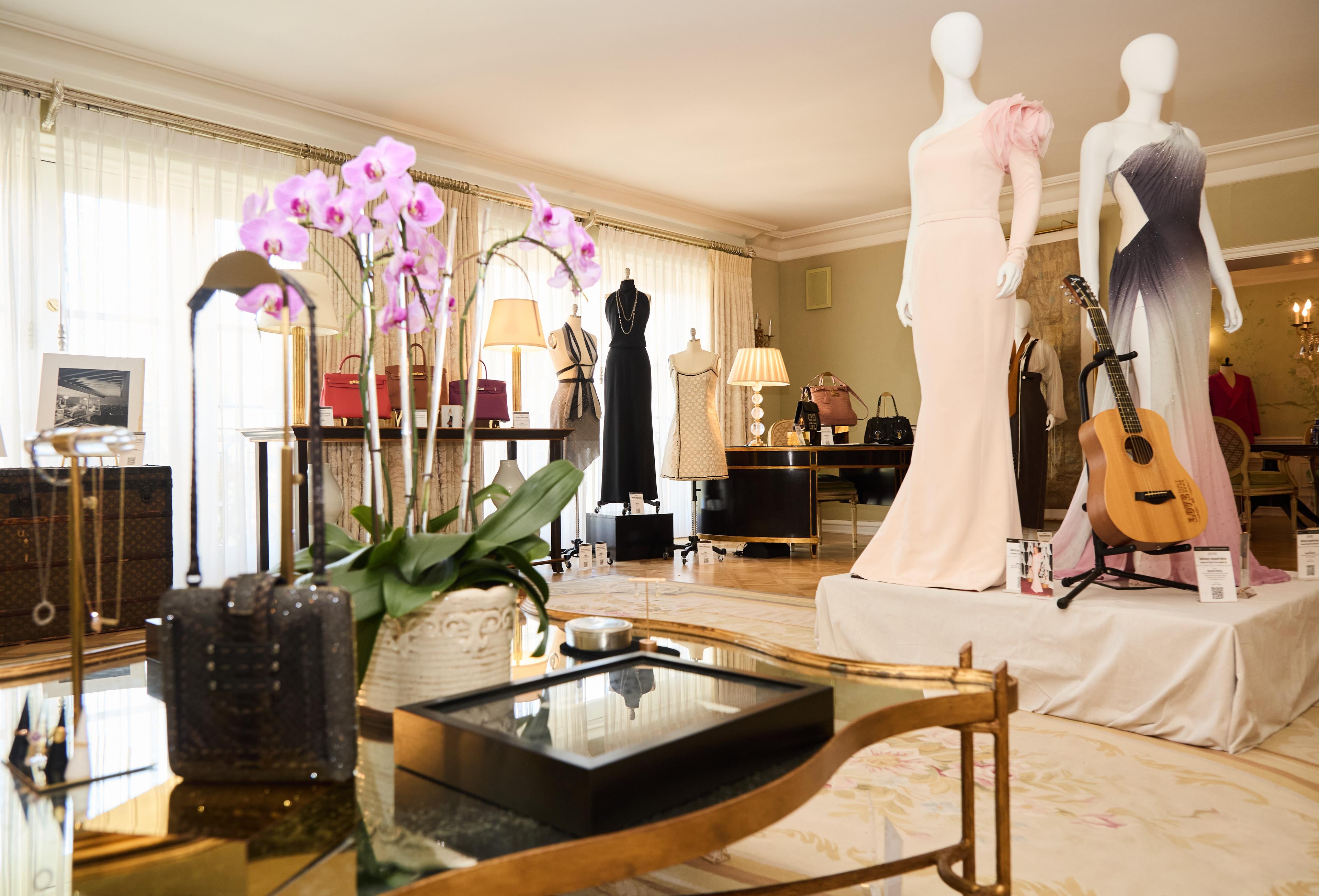 mannequins wearing dresses and floral arrangements on a table at gwyneth paltrow auction press preview at the peninsula beverly hills