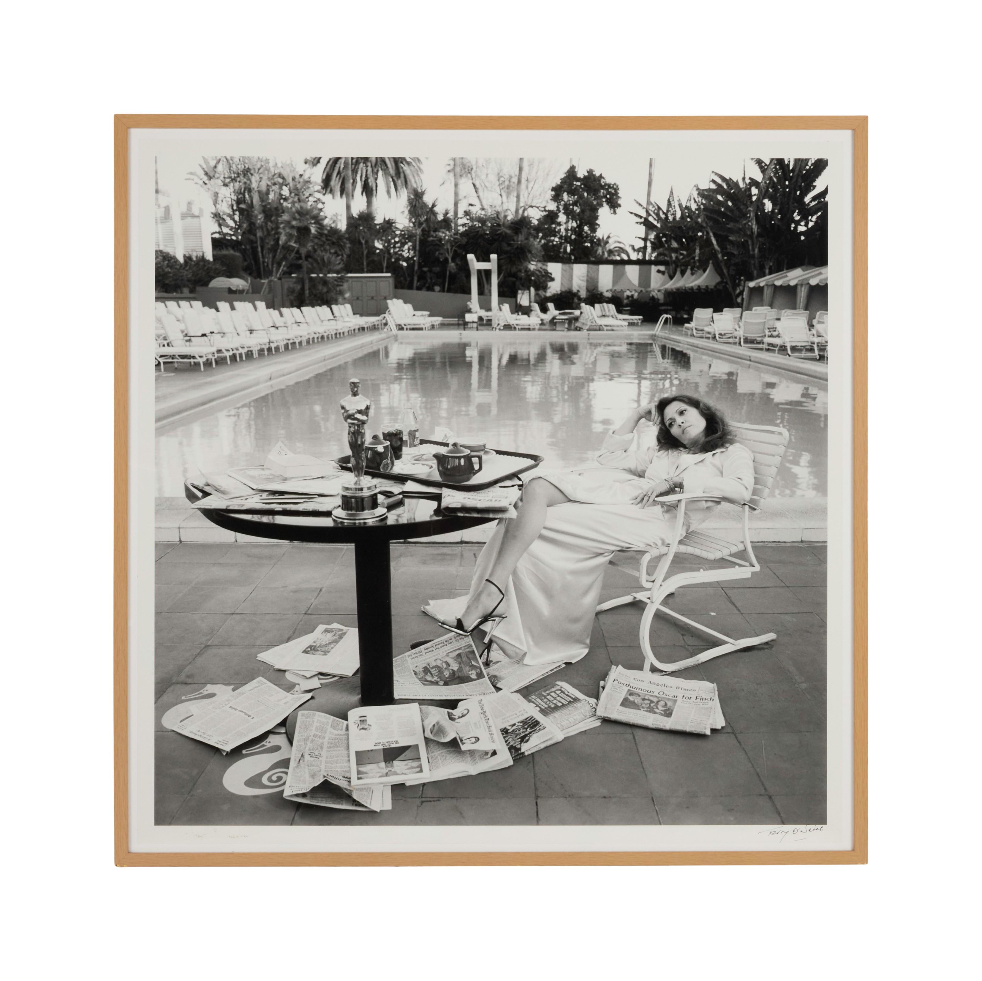 a black and white photo of a woman sitting at a table next to a pool .