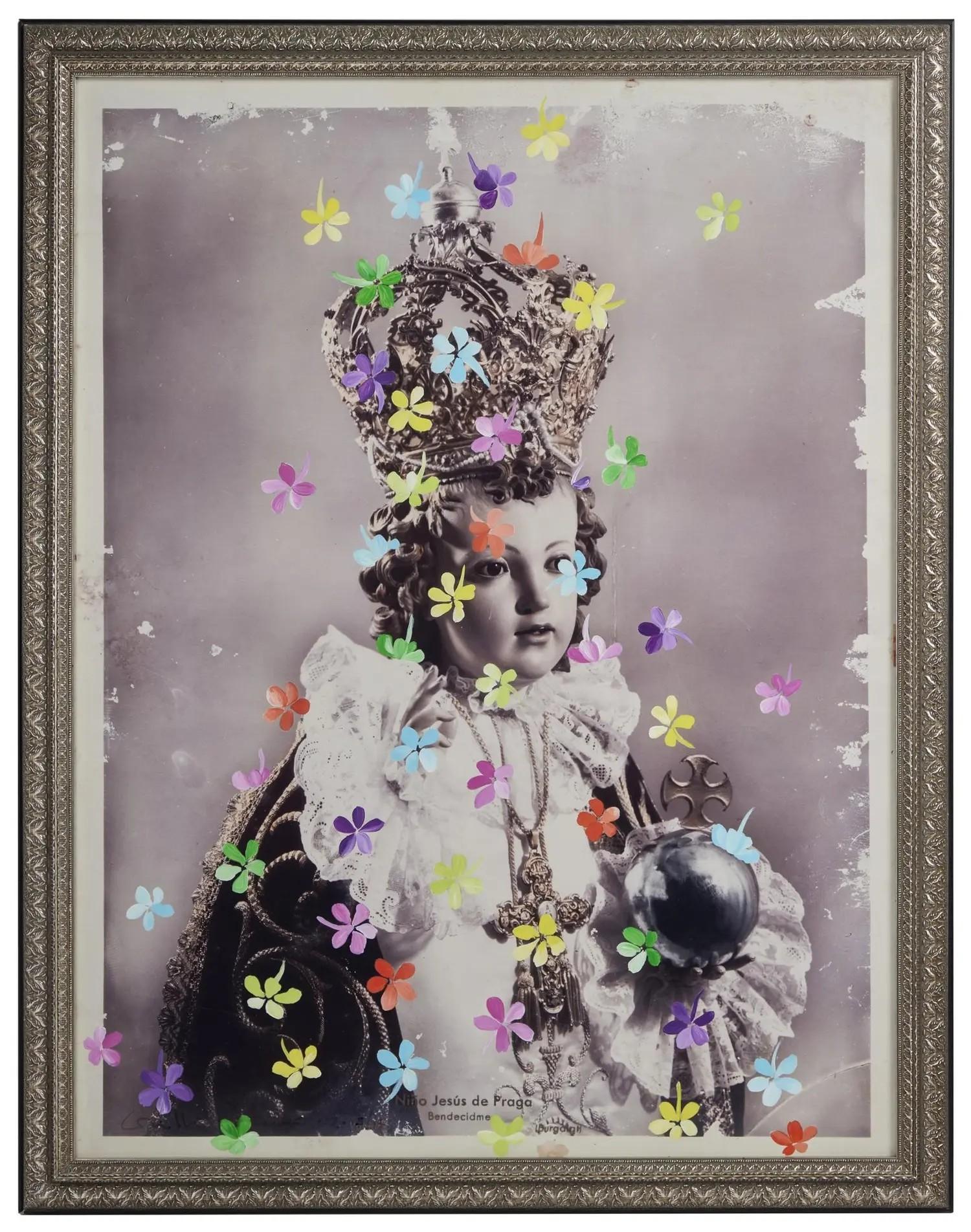 Lot #37. Grillo Demo | Signed and Hand-Embellished "Bambino with Falling Jasmine" Artwork Framed black and white photo of the crowned Infant Jesus of Prague statue, adorned with colorful paper flowers.