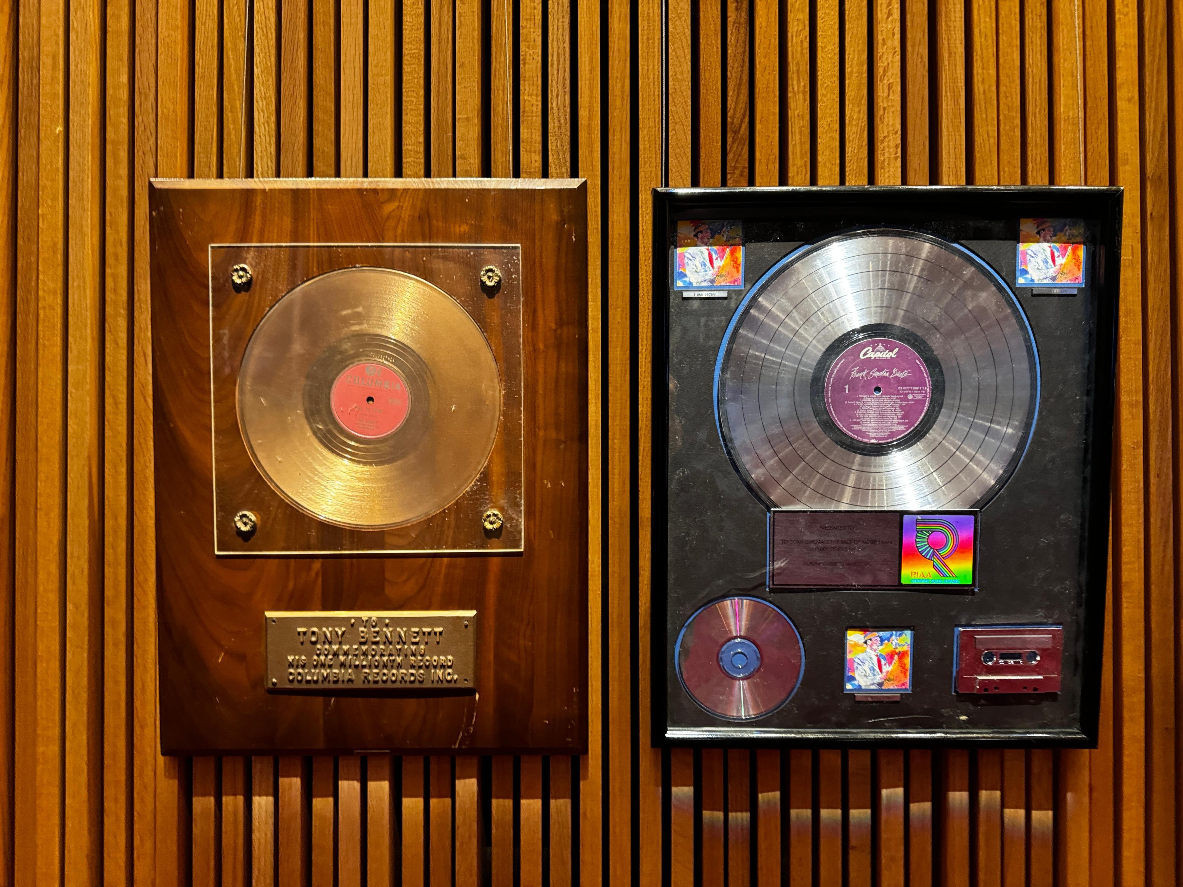 two plaques with records on them are hanging on a wooden wall .