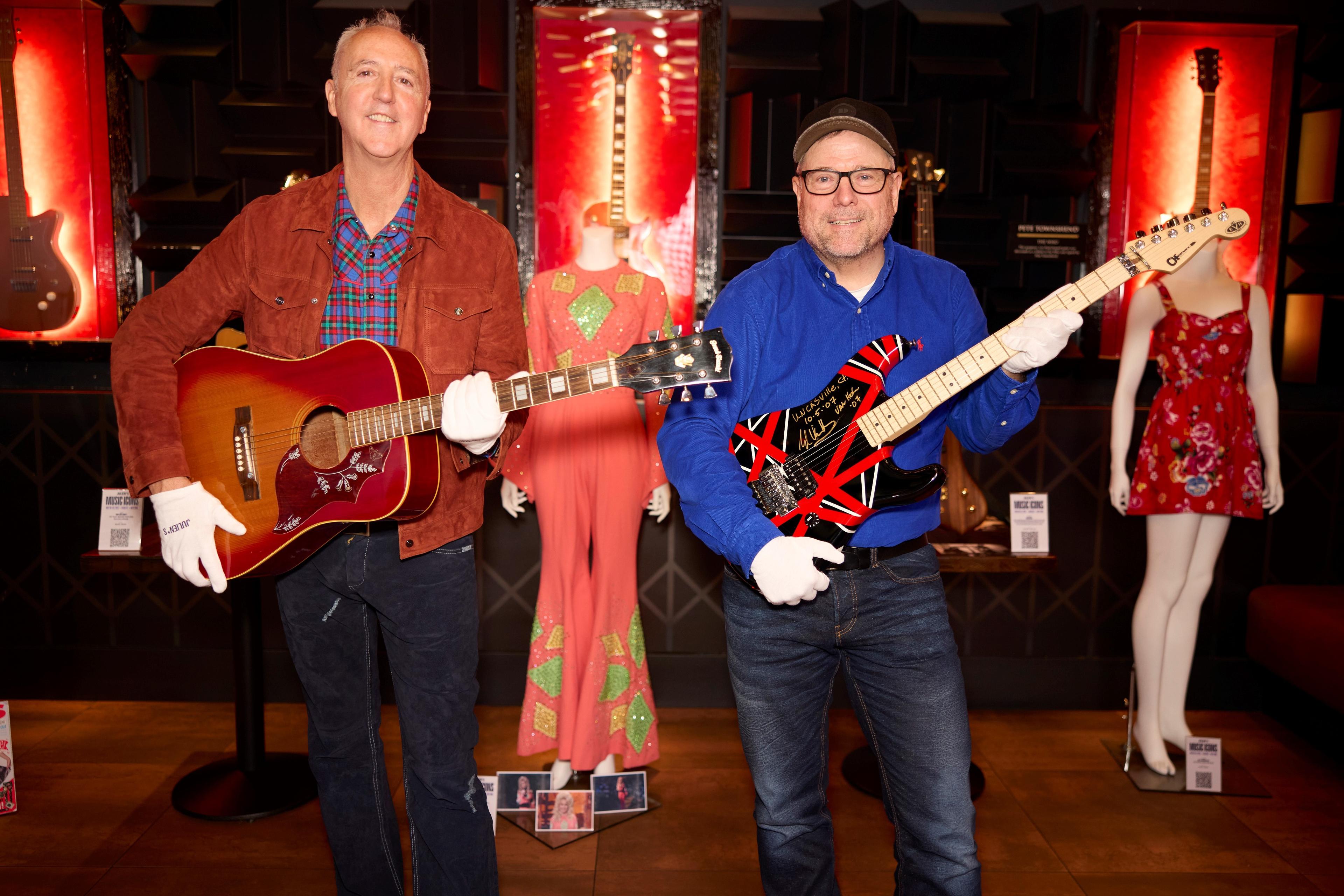 two men each holding a guitar