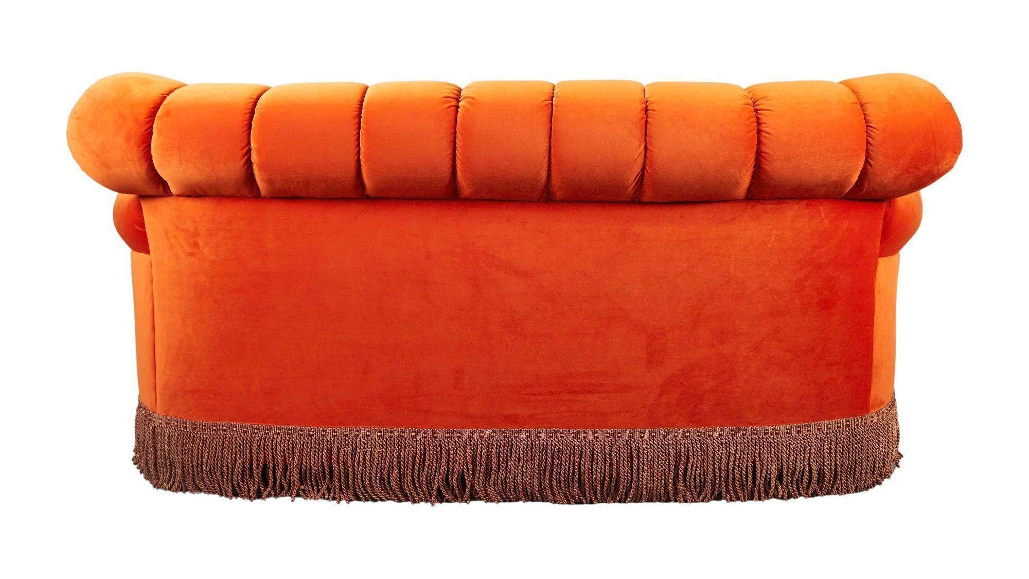 the back of an orange couch with fringe on a white background .