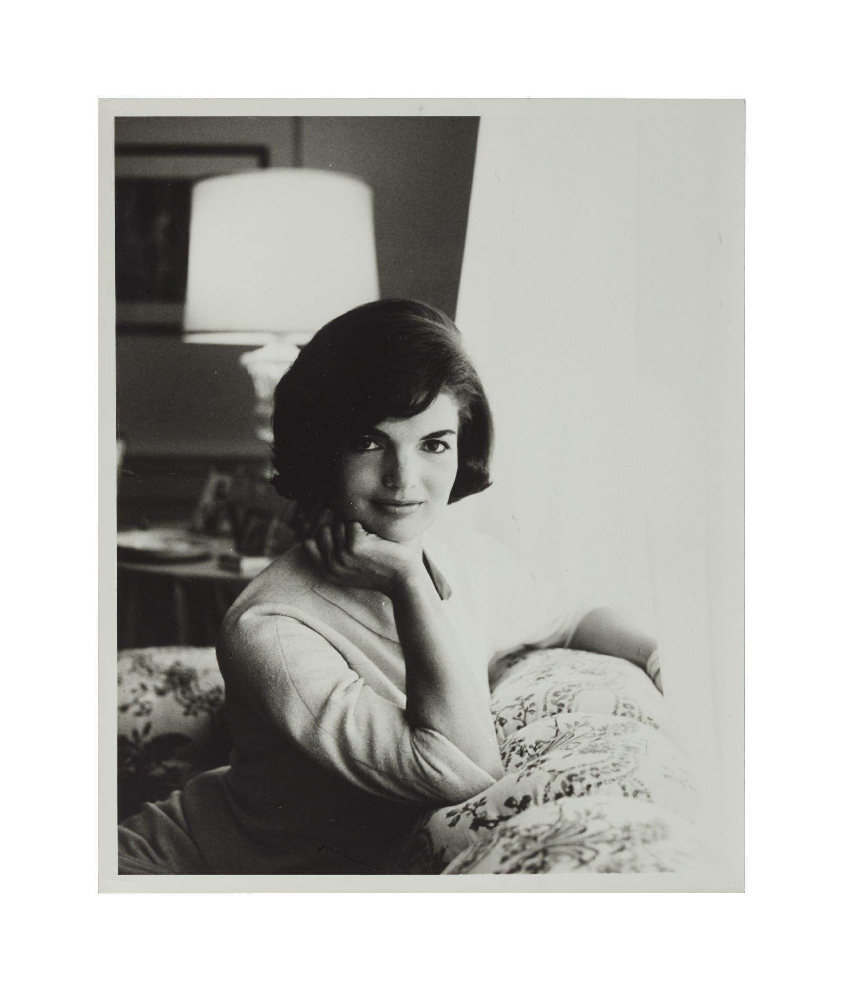 a black and white photo of a woman with her hand on her chin