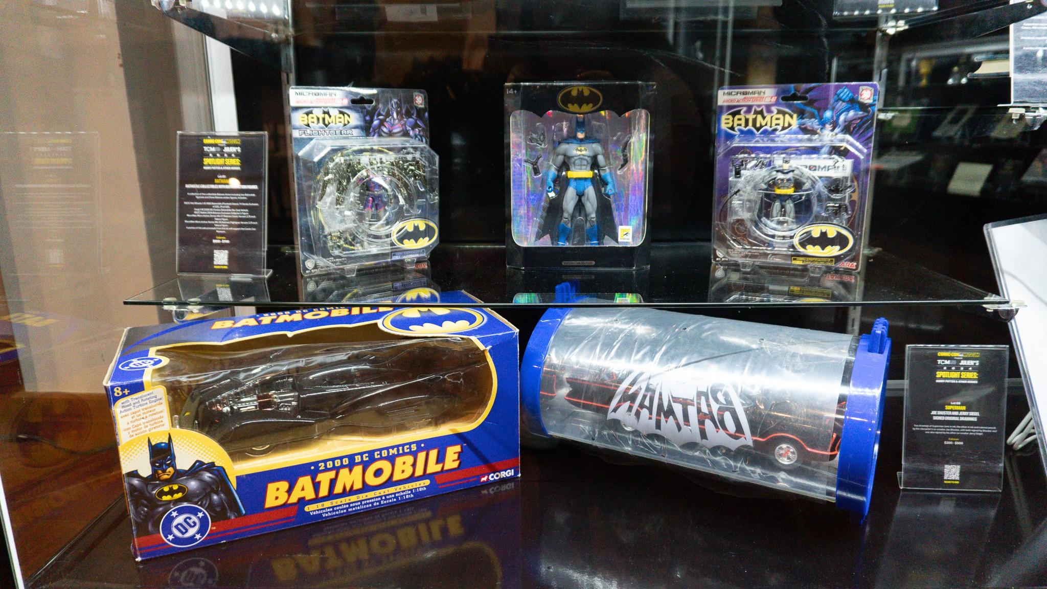 a display case filled with a variety of batmobile toys .