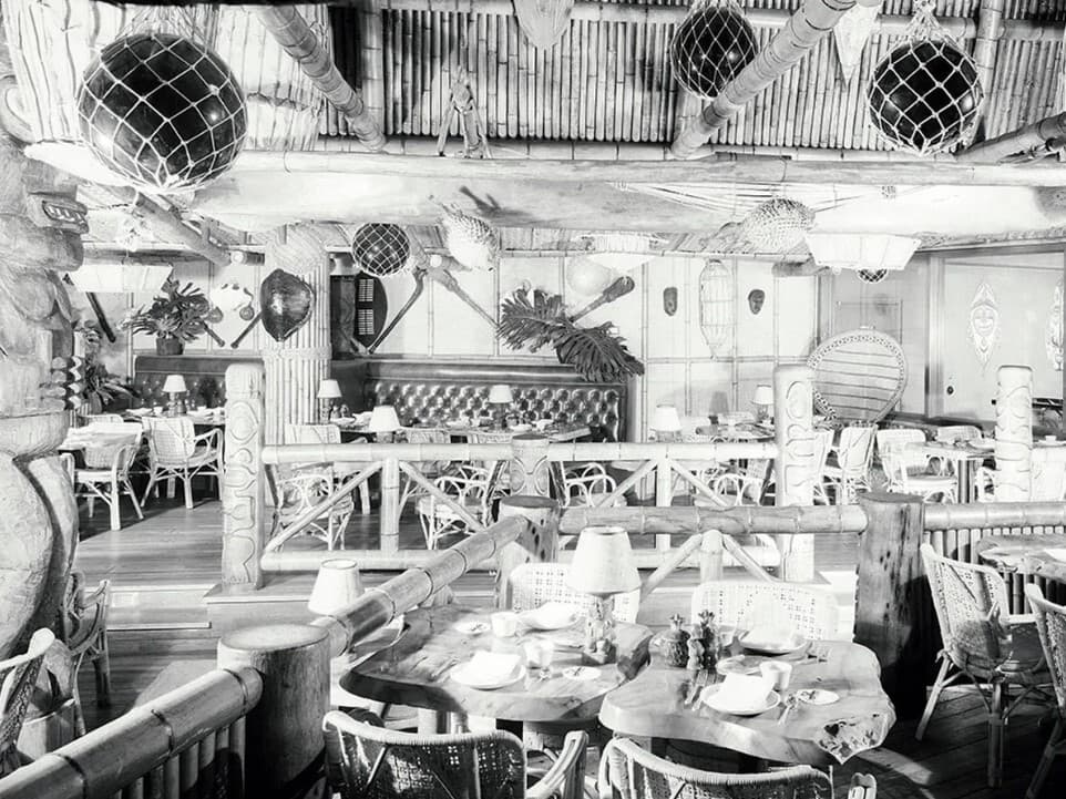 a black and white photo of a restaurant with tables and chairs .