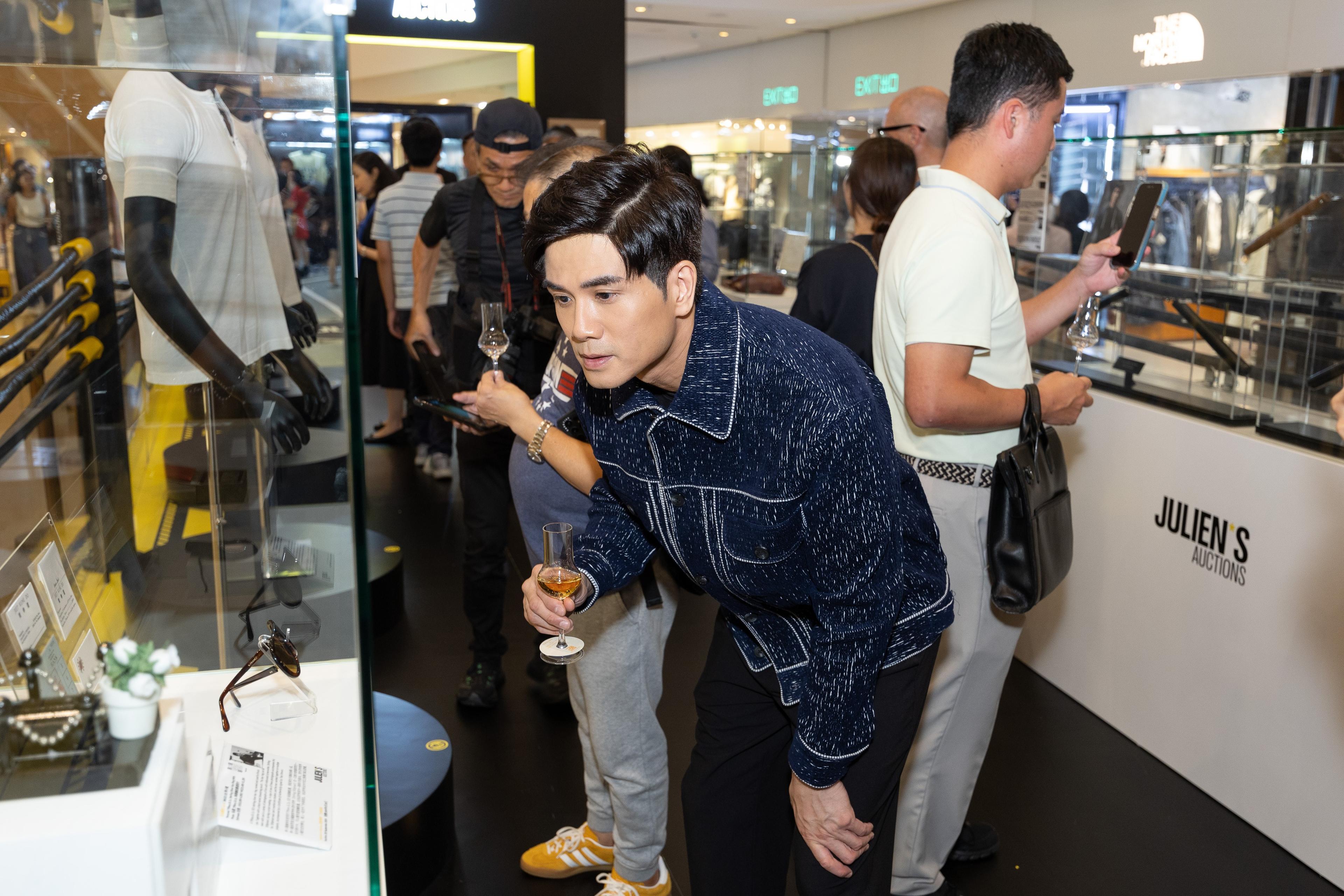 a group of people are looking at sunglasses in a glass display case.