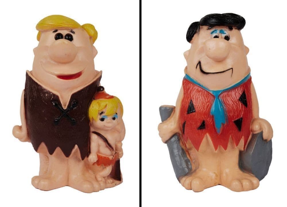 two plastic figurines of flintstone from the flintstones are sitting next to each other on a white background .