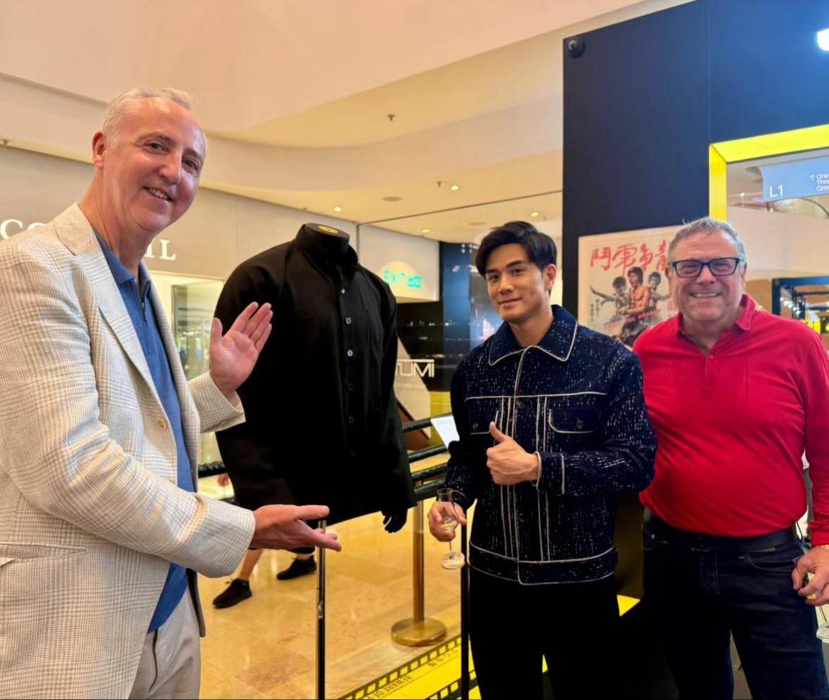 three men are standing next to each other in front of a mannequin .