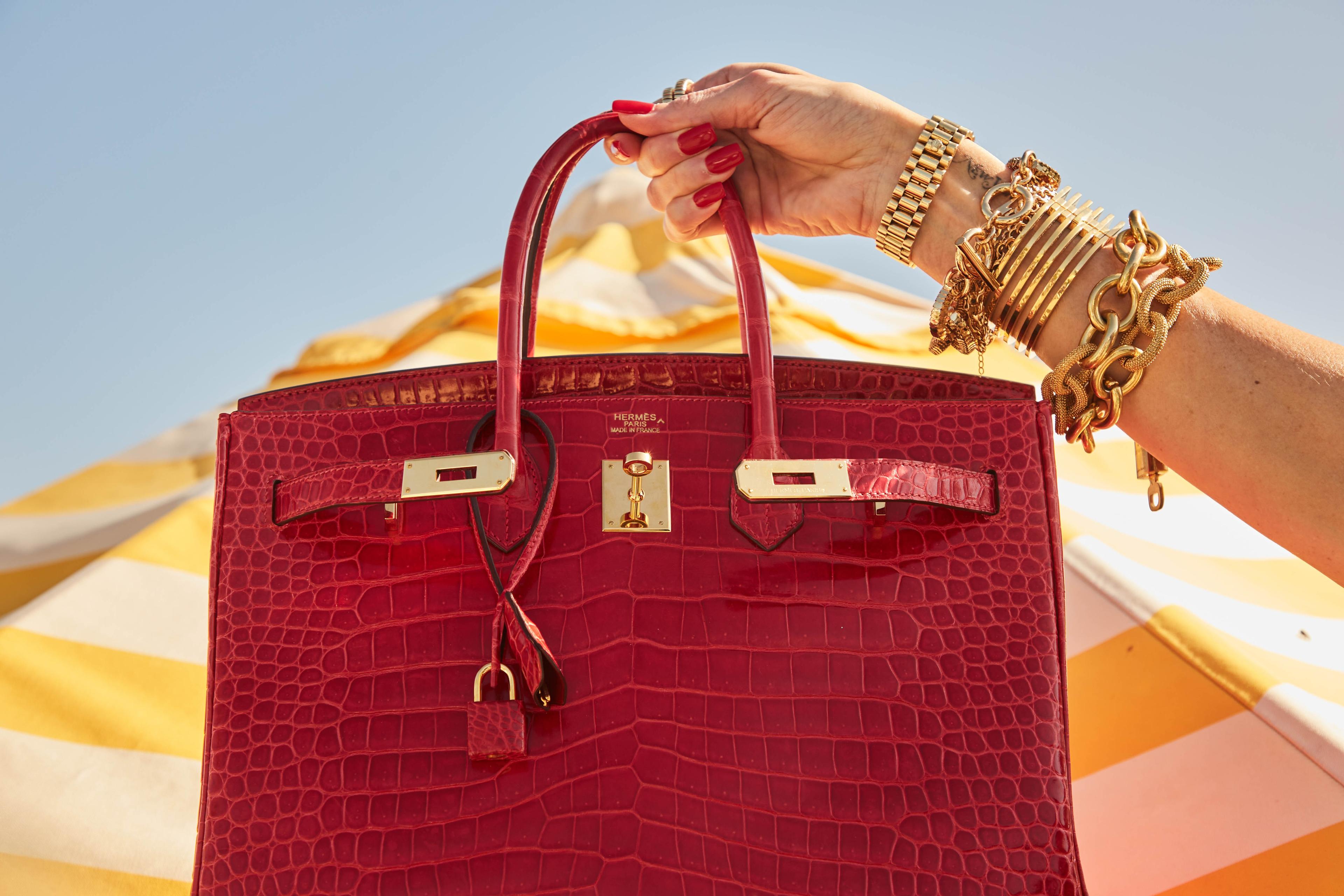 a woman is holding a red purse in her hand .